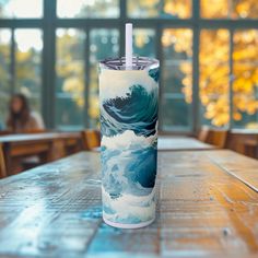 a blue and white cup sitting on top of a wooden table next to a window