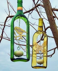 two wine bottles hanging from a tree with birds painted on them and one has an egg in it