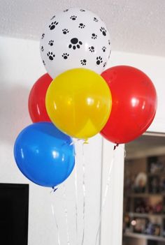 a bunch of balloons with paw prints on them hanging from a ceiling in a room