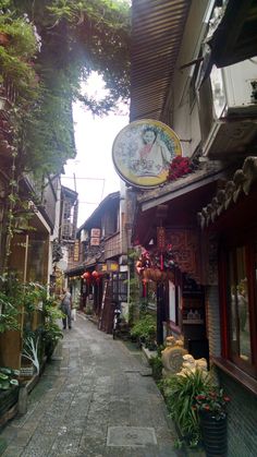 an alley way with shops and plants on both sides