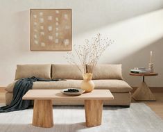 a living room with a couch, coffee table and vase on the floor in front of it