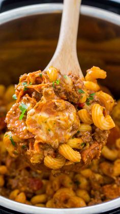 a wooden spoon full of macaroni and cheese being lifted from the crock pot