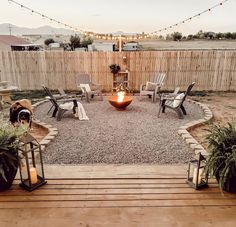 an outdoor fire pit surrounded by chairs and potted plants with lights strung over it