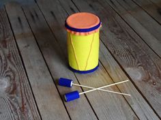 an orange and blue container sitting on top of a wooden floor next to two sticks