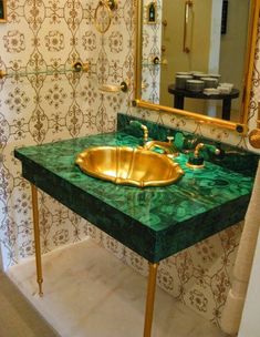 a bathroom with green marble counter top and gold faucet sink in front of mirror