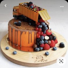 there is a cake with fruit on it and a dump truck on the top one