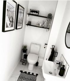 a black and white photo of a bathroom with pictures on the wall above the toilet