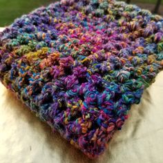 a multicolored crocheted blanket sitting on top of a white tablecloth