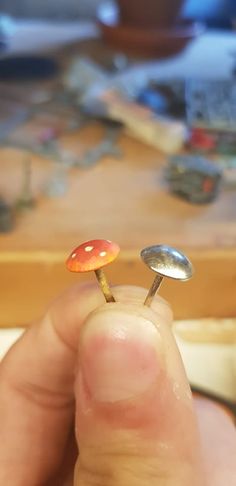 a tiny mushroom sitting on top of a metal object in someone's hand next to a table