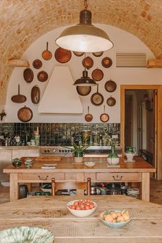 a wooden table topped with bowls of fruit next to a kitchen oven and counter top