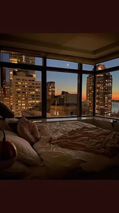 a bed in front of a large window with city lights out the windows at night