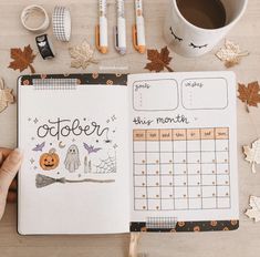 a person holding a pen and looking at an open planner with halloween decorations around it