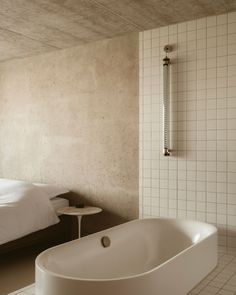 a large white bath tub sitting next to a bed