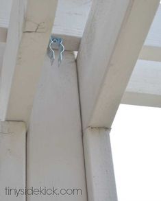 a blue pair of scissors hanging from the side of a white wooden structure with wood slats