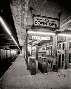 black and white photograph of an old subway station with the exit to his st sign