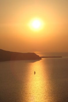 the sun is setting over an ocean with a boat on it's back end