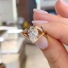 a woman's hand holding an engagement ring with a diamond in the middle and a gold band around it