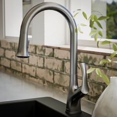 a kitchen sink with a faucet next to a window and a potted plant