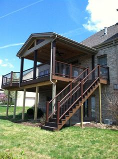 a two story house with stairs leading up to the second floor and an attached deck