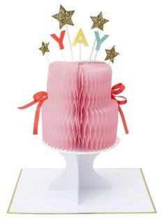 a pink cake with gold stars on top and the words yay spelled in small letters