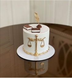 a white cake with gold decorations on top and a golden feather sitting on top of it