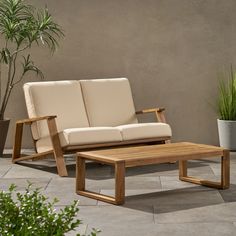 a couch and coffee table sitting in front of a potted plant on a patio