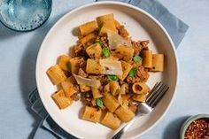 a white plate topped with pasta and meat next to a bowl of chili seasoning