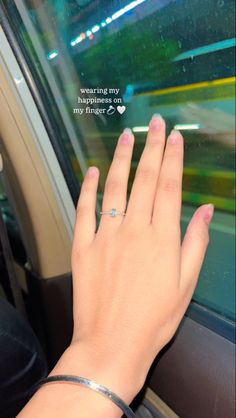 a woman's hand with a ring on her finger, sitting in a car