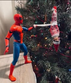 a spiderman toy standing next to a christmas tree