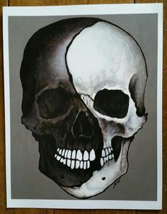 a drawing of a skull on a wooden surface with the lower half painted black and white