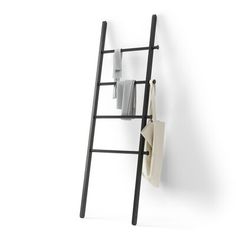 a ladder leaning against a wall with towels hanging from it's sides and folded paper on the other side