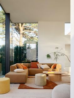 a living room filled with lots of furniture and large glass windows on the side of it