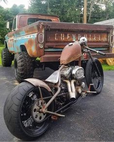 an old rusted out motorcycle parked in front of a truck