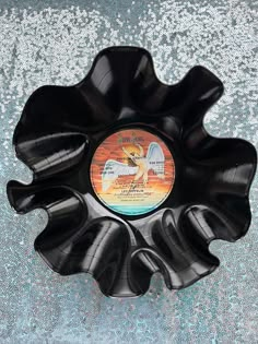 a black flower shaped bowl with an image of a bird on it's side