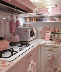 a kitchen with pink and white decor on the walls, cabinets and stove top oven