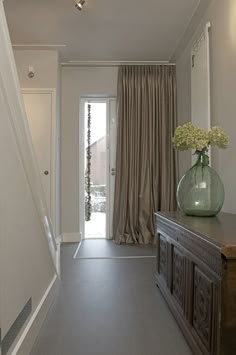 a vase with flowers sitting on top of a dresser in front of a door way