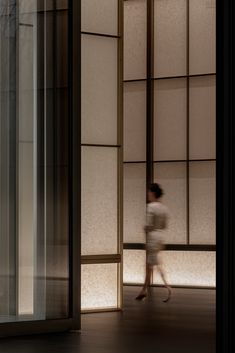 a woman walking through an empty room with large windows