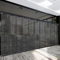 an empty room with wooden flooring and black curtains on the wall, in front of a large window