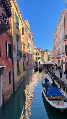 boats are parked along the side of a canal in an old city with colorful buildings