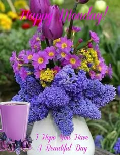 a vase filled with purple flowers next to a cup