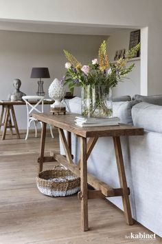 a white couch sitting next to a table with flowers on it in a living room