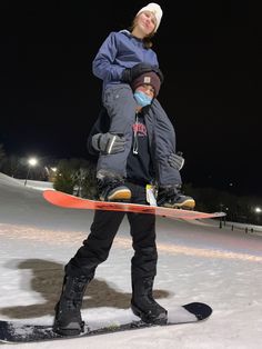 a man holding a child on top of a snowboard