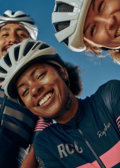 three people wearing helmets and smiling at the camera with blue sky in the back ground