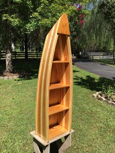 a wooden boat shaped book shelf sitting in the grass