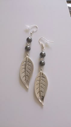 the earrings are made with silver beads and leaf shaped pendants on top of each other