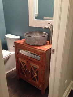 a bathroom sink sitting on top of a wooden cabinet in front of a toilet and mirror