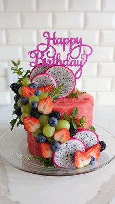 a birthday cake decorated with fruit and the words happy birthday written on top of it