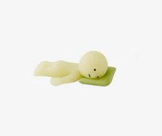 a small white toy laying on top of a green object