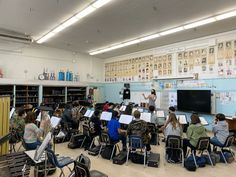 a group of people sitting in front of desks with sheet music on the wall