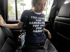 a woman sitting in the back seat of a car wearing a t - shirt that says too loud for barcelona too shy for madrid